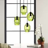 Green pendants in three shapes hung in a black window frame