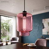 Pink glass pendant lit above a dining table in a blue walled room