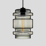 Smoke grey ribbed glass pendant with stacked rings, shown lit