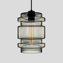Smoke grey ribbed glass pendant with stacked rings, shown lit