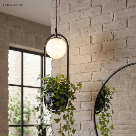 Planter pendant with a globe light hanging by a white brick wall