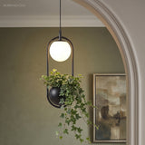 Hoop planter pendant lit above a teal sofa in a green room