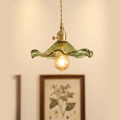 Green hibiscus glass pendant with a brass holder above a framed botanical print