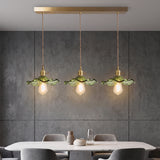 Three green hibiscus shades on a brass bar against a grey concrete wall