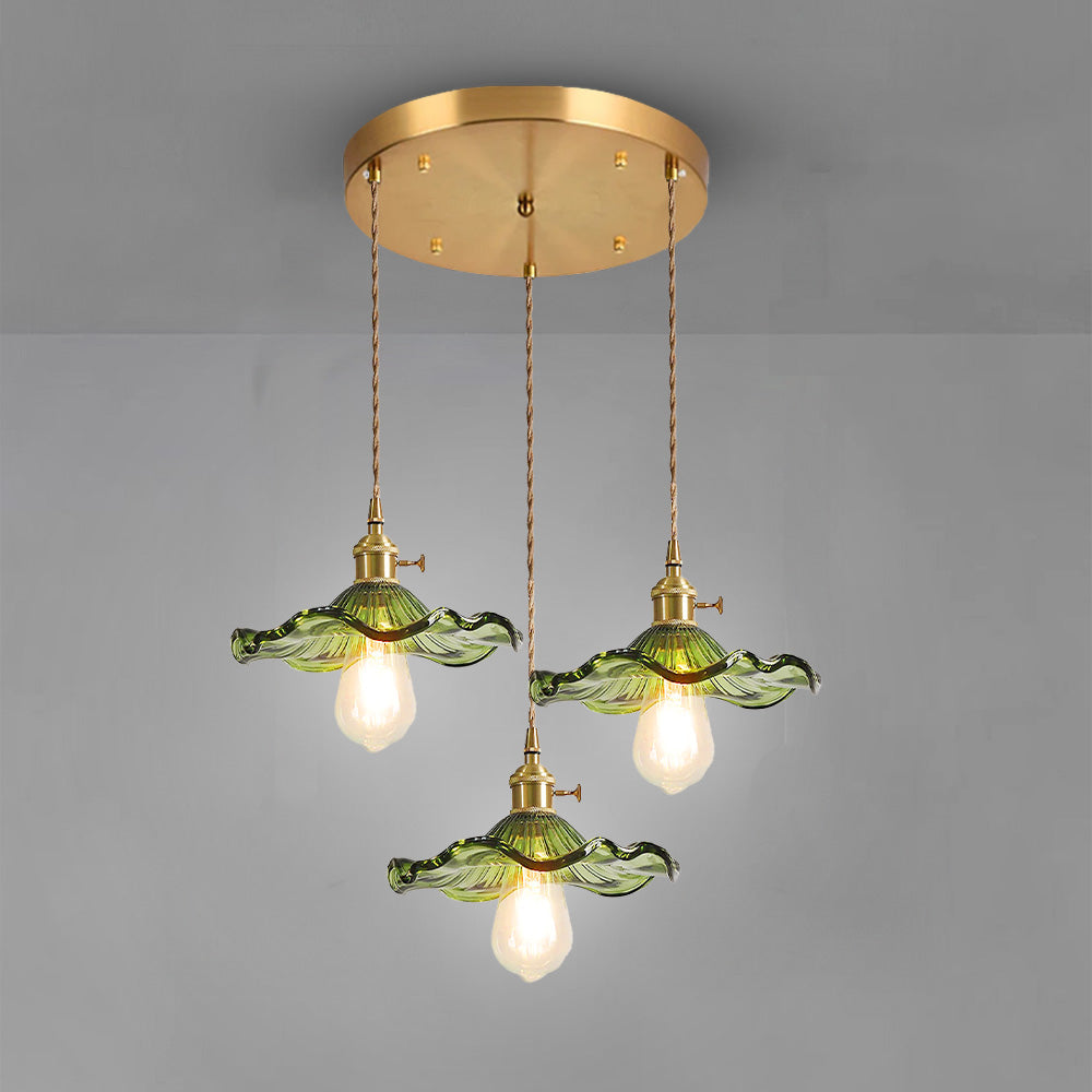 Three green scalloped pendants hanging from a single round brass ceiling plate