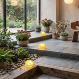 Warm white glass cube lights along a stone patio step beside potted plants