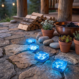 Blue glowing cube lights set into a stone patio next to a stacked log store