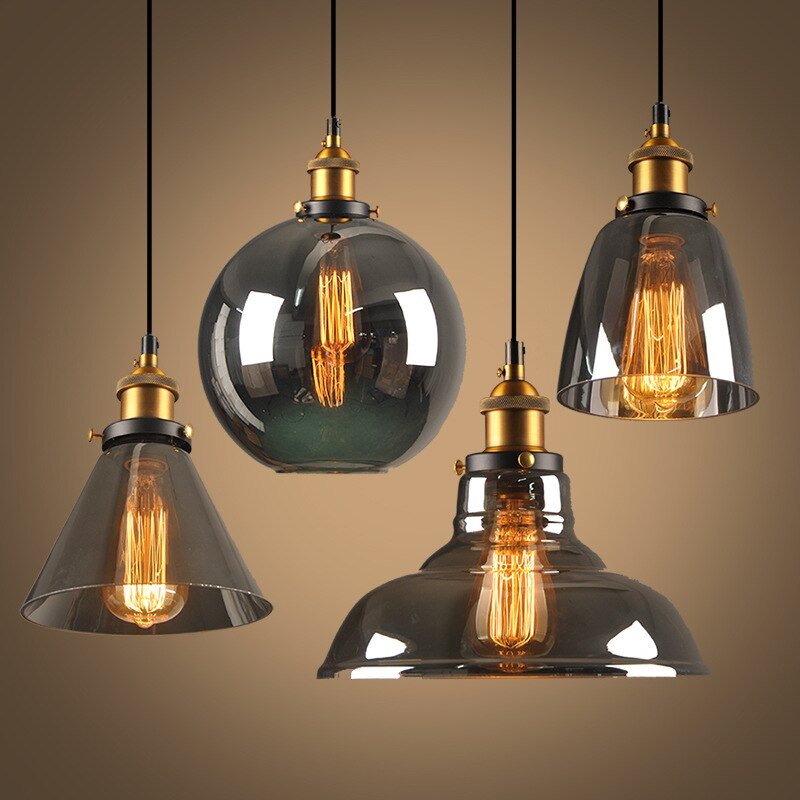 Four smoke and amber glass pendants lit together against a warm backdrop