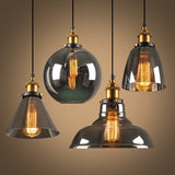 Four smoke and amber glass pendants lit together against a warm backdrop