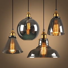 Four smoke and amber glass pendants lit together against a warm backdrop