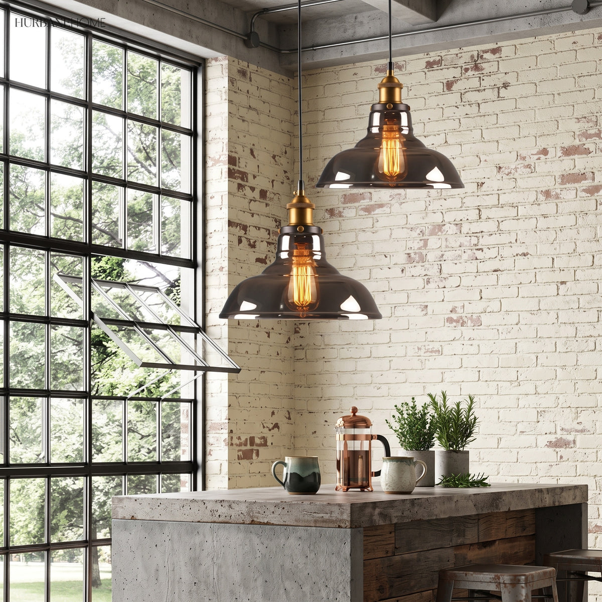 Two glass pendant lights above a concrete kitchen island beside a steel window