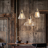 Three clear glass pendant lights above a rustic dining table and weathered timber