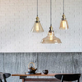 Three clear glass pendants above a dark marble counter and white brick wall