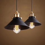 Two cone pendants with filament bulbs against a warm amber backdrop