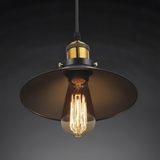 Black cone pendant with a brass cap lit against a dark grey wall