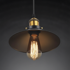 Black cone pendant with a brass cap lit against a dark grey wall