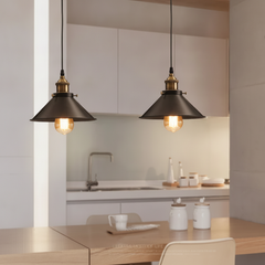 Two black pendants hung above a pale kitchen island and stools