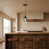 A single black metal pendant light with a wire cage shade hangs above a wooden kitchen island with three brown leather bar stools in a modern, warm-toned kitchen.