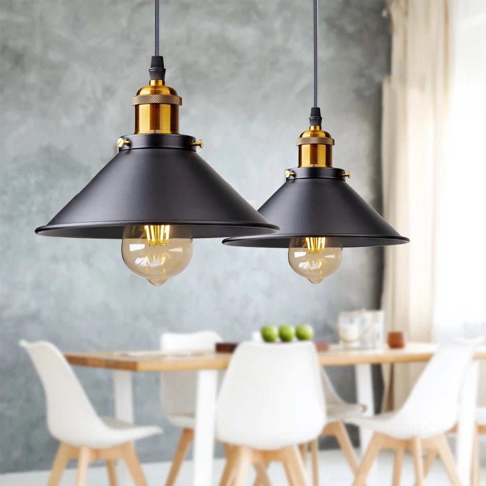 Two black cone pendants lit above a pale dining table and chairs