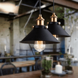 Three black cone pendant lights hanging over a cafe counter