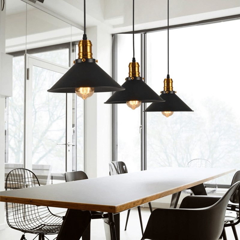Three black cone pendants hanging above a long white office table