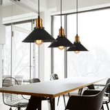Three black cone pendants hanging above a long white office table
