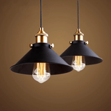 Two black cone pendants with brass sockets lit against a warm backdrop