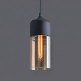 Amber cylinder shade with a black metal cap on a grey background