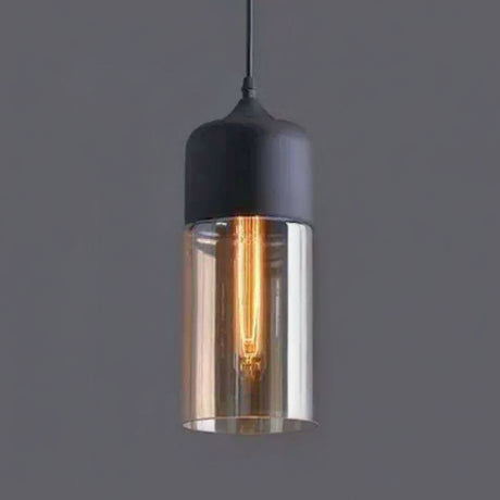 Amber cylinder shade with a black metal cap on a grey background
