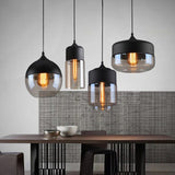 Four glass pendants lit above a dining table against a textured wall