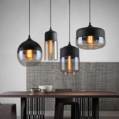 Four glass pendants lit above a dining table against a textured wall