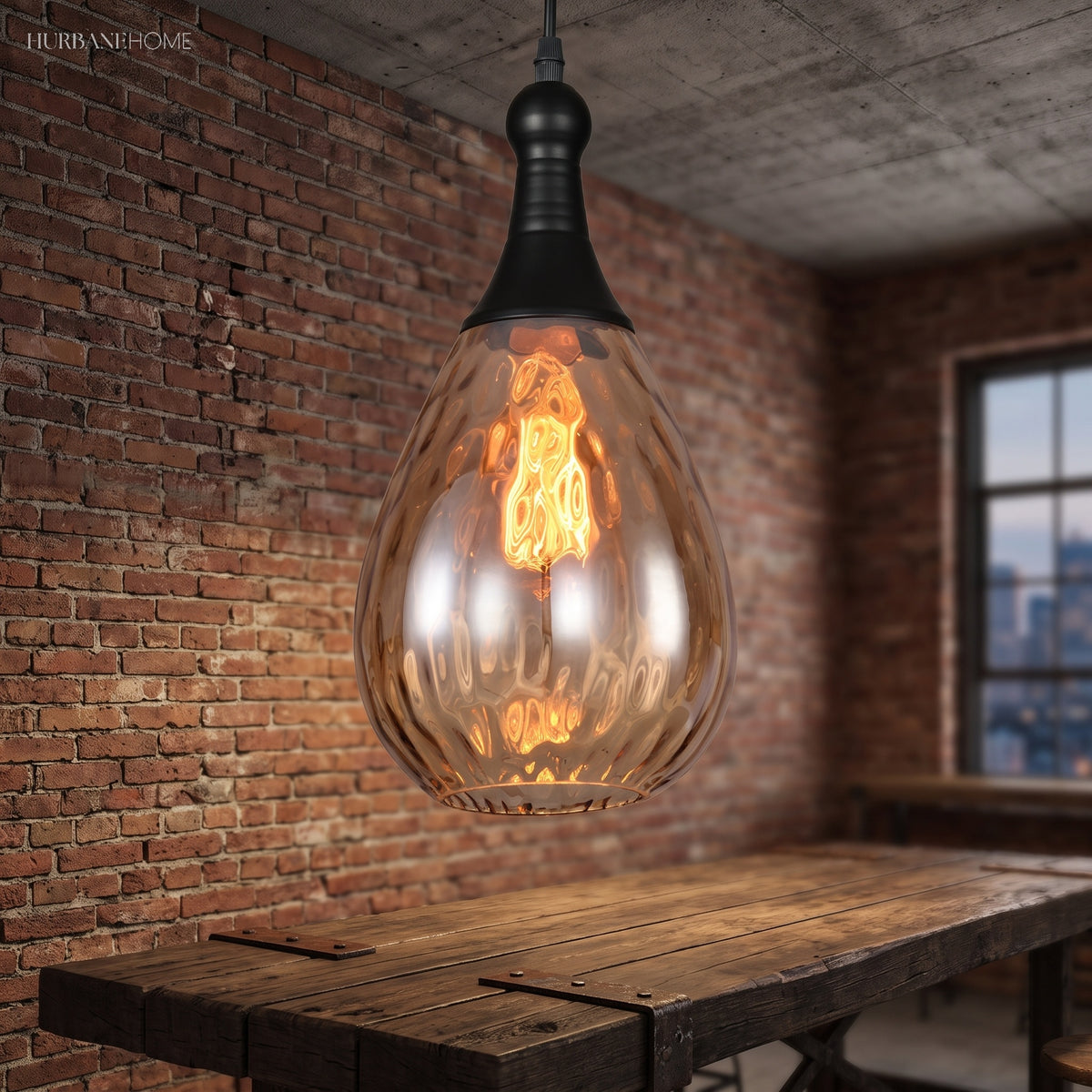 Teardrop pendant glowing over a long timber table by a brick wall