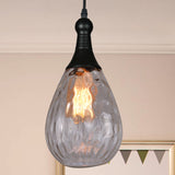 Clear dimpled teardrop pendant lit in a pale room with bunting