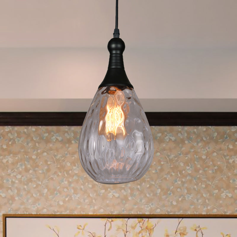 Clear teardrop pendant lit beside a framed picture on a cream wall