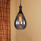 Smoke teardrop pendant lit beside a patterned orange curtain