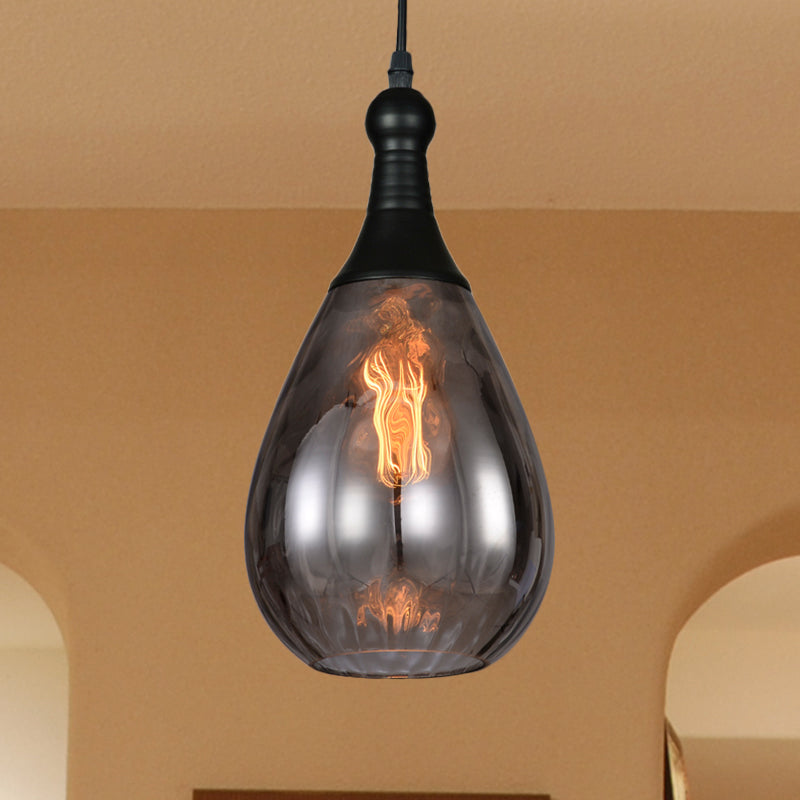 Smoke teardrop pendant lit against a tan wall beside a rounded arch