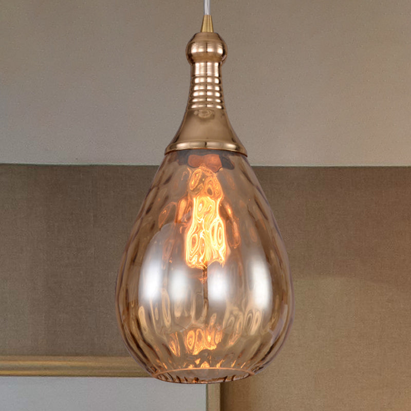 Amber teardrop pendant lit against a grey tiled splashback