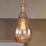 Amber teardrop pendant lit against a grey tiled splashback