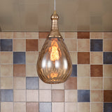 Amber teardrop pendant in front of a coloured mosaic tile wall