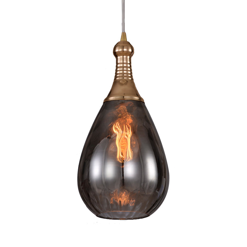 Brass capped teardrop pendant lit warm against a plain backdrop