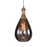 Brass capped teardrop pendant lit warm against a plain backdrop