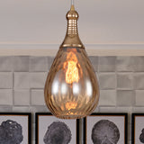 Amber teardrop pendant over white tiles beside three framed prints