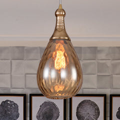 Amber teardrop pendant over white tiles beside three framed prints