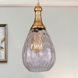 Clear teardrop pendant beside framed art and a small potted plant