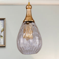 Clear teardrop pendant beside framed art and a small potted plant