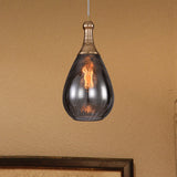 Smoke teardrop pendant hanging beside a framed print on a dark wall