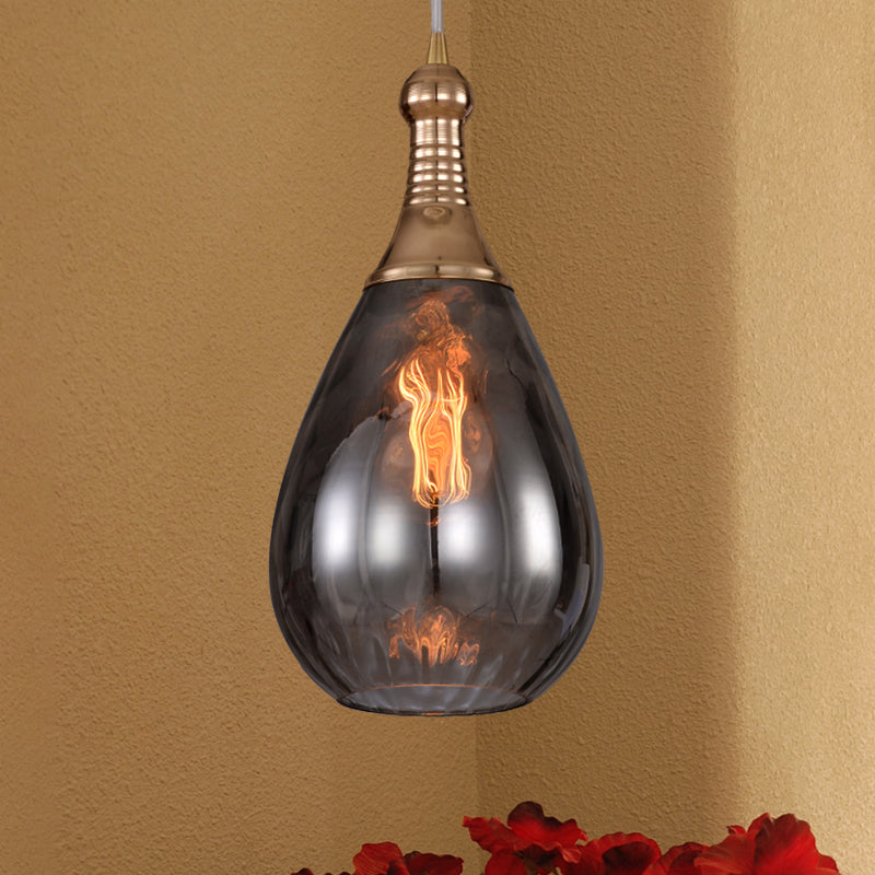 Smoke glass teardrop pendant on an ochre wall above red flowers