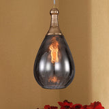 Smoke glass teardrop pendant on an ochre wall above red flowers