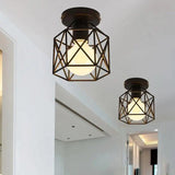 Two black cage lights on a white ceiling above a bright hallway