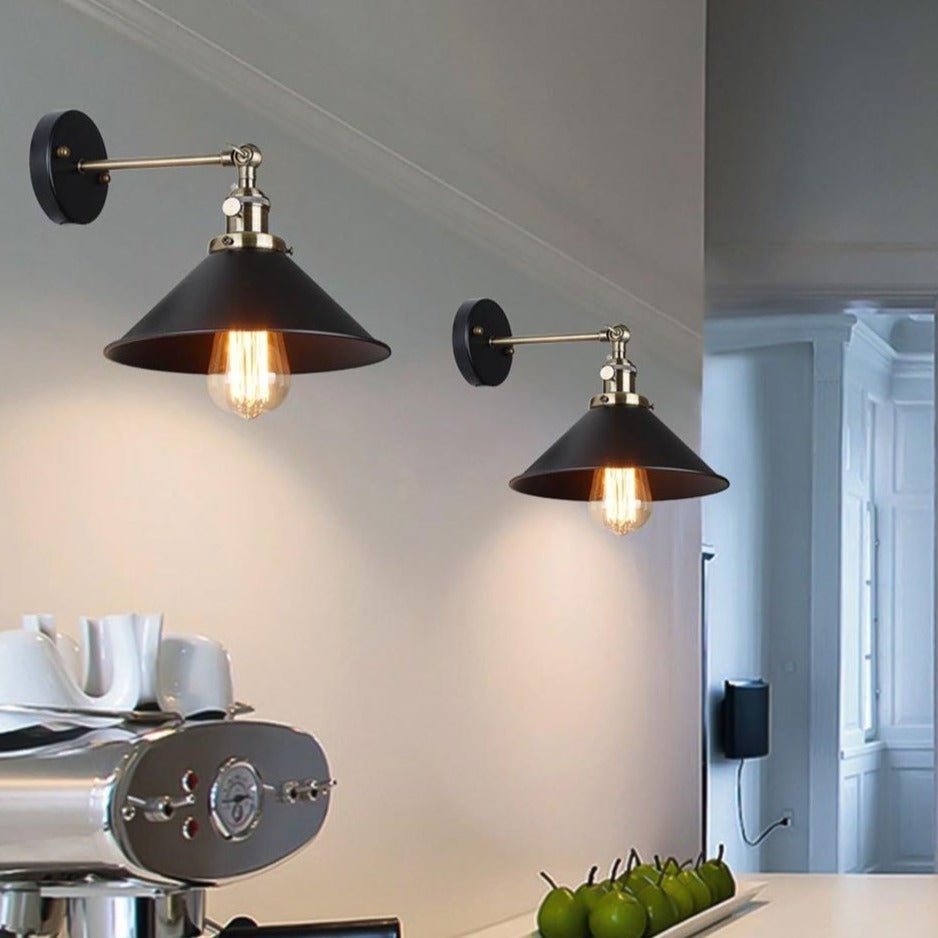 Two cone shade wall sconces with brass fittings lit in a white kitchen